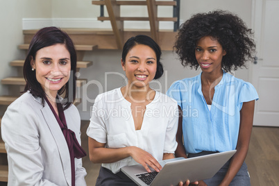 Female business colleagues discussing on laptop