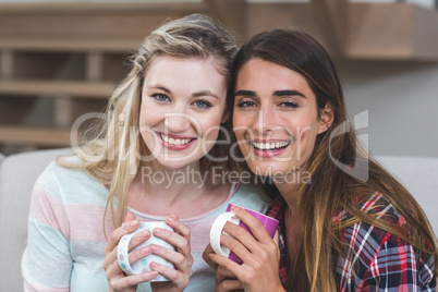 Two beautiful women sitting side by side with a mug of coffee