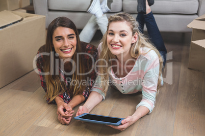 Friends lying together on the floor and using digital tablet