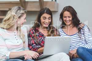 Friends sitting on sofa and using laptop