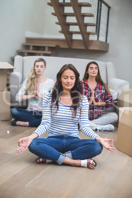 Friends performing yoga in their new house