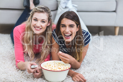 Two beautiful women having popcorn and watching television in li