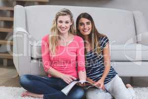 Two beautiful women with magazine in living room