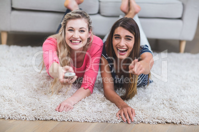 Two beautiful women watching television in living room