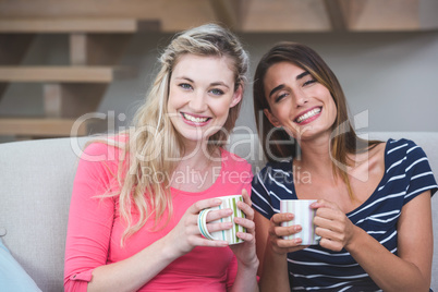 Two beautiful women sitting side by side with a mug of coffee