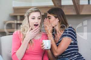 Young woman whispering a secret to her friend