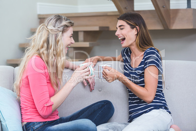 Two beautiful women holding a cup of coffee and talking in the l