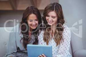 Two beautiful women using a digital tablet in living room