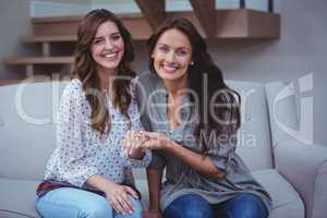 Two beautiful women sitting on sofa and holding hands