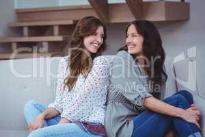 Two beautiful sitting back to back on sofa