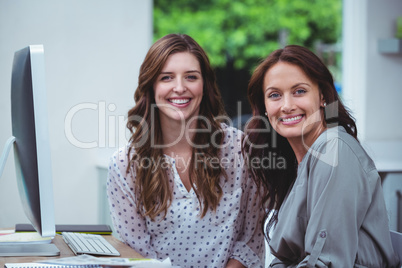 Portrait of two women sitting in front of computer