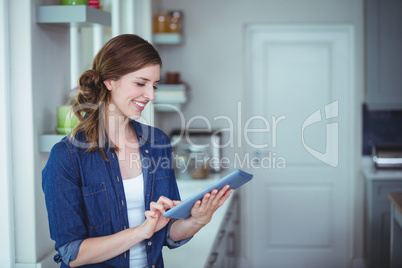 Beautiful woman using digital tablet in kitchen