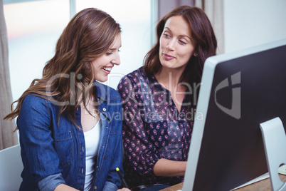 Two women interacting with each other in front of computer