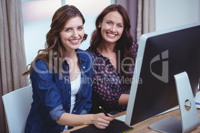 Portrait of two women sitting in front of computer