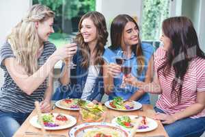 Friends toasting glass of red wine while having meal
