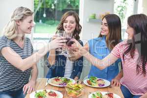 Friends toasting glass of red wine while having meal