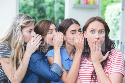 Women in a row whispering secrets in their friends ears