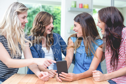 Cheerful women looking at mobile phone and laughing