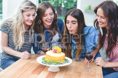 Woman blowing the candles on her birthday cake with her friends