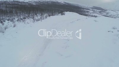 Aerial view of car driving on snowy mountain road
