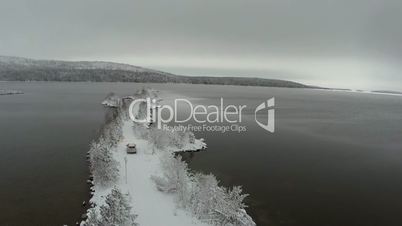Car driving on winter island road in the river, aerial view