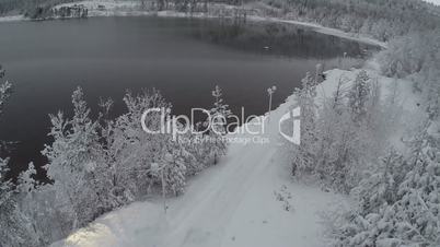 Car getting to winter recreation through pine wood, aerial view
