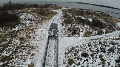 Aerial view of car driving away from shore in winter