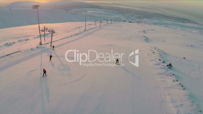 Aerial view of skiers and snowboarders at sunset