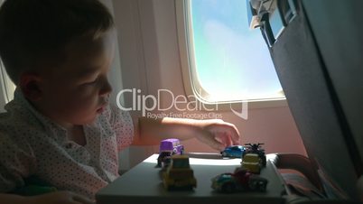Little kid playing with toy cars in the airplane
