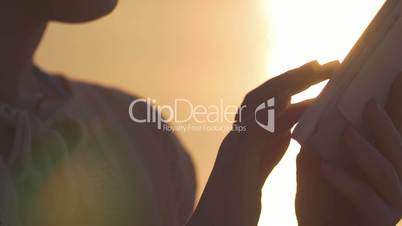 Woman with tablet computer at summer sunset