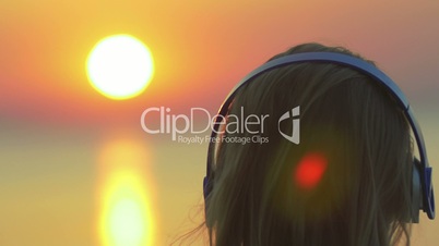 Woman enjoying music and sunset