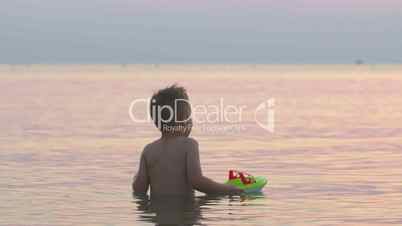 Boy Playing with Toy Boat in Sea