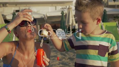 Mother and Son Blowing Soap Bubbles on the Beach