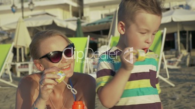 Mother and child blowing bubbles on the beach