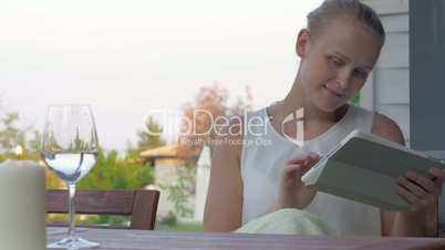 Woman using pad and drinking water in outdoor terrace