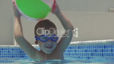 Little playful child with ball in pool