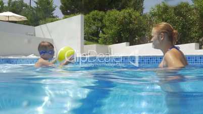 Mother and son playing with ball in the pool