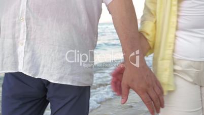 Senior couple holding hands during walk on beach