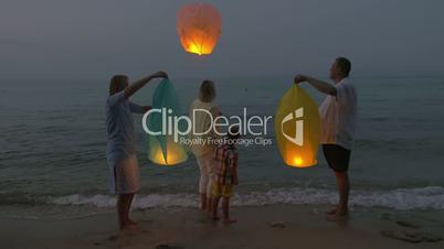 Family flying sky lantern on the beach