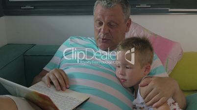 Child and grandfather using laptop at home