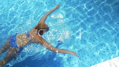 Woman swimming in the pool on hot sunny day