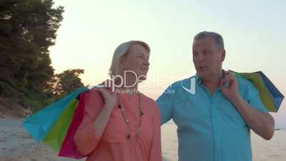 Mature couple relaxing with seaside walk after shopping