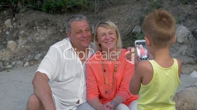 Child taking picture of grandparents with cell phone