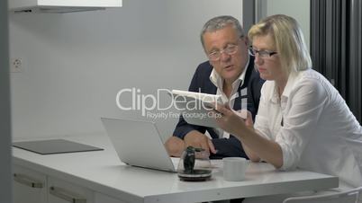 Couple of adults with pad in kitchen