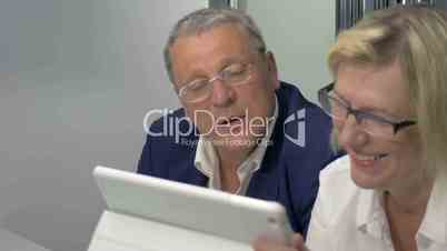 Mature man and woman doing business with tablet PC