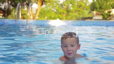 Cute little child bathing in outdoor swimming pool