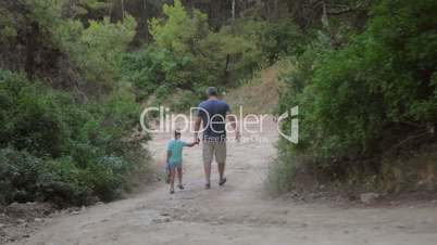 Father and son walking away in forest