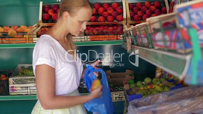 Young woman choosing pears in fruit shop