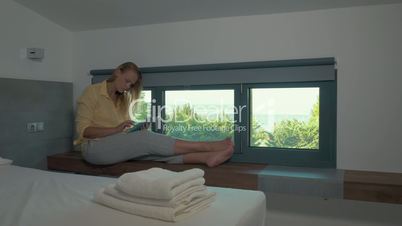 Woman using pad by the window in hotel