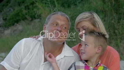 Grandson tickling grandfather's neck while sitting on beach